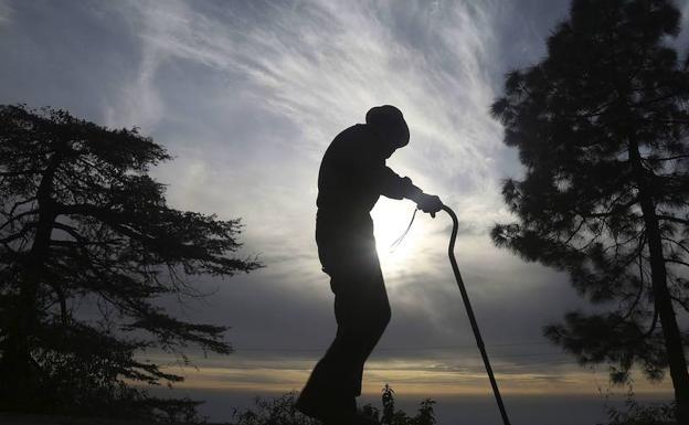 Un anciano camina por los alrededores de una residencia.