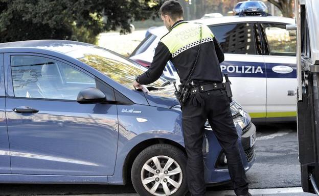 Un agente coloca una multa en el parabrisas de un coche en Vitoria. /I. Aizpuru