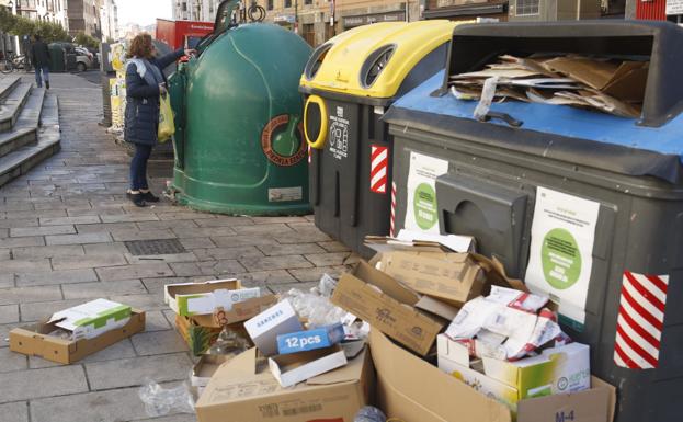Una vecina deposita la basura en un buzón frente a un contenedor con basura en el exterior./Rafa Gutiérrez