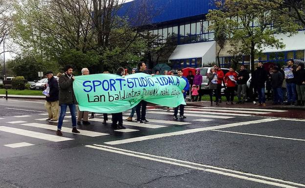 Parte de los monitores subcontratados de Getxo Kirolak ayer, con una pancarta en la carretera. /e. c.