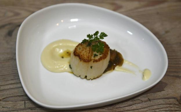 A la viera, grande, traída de Galicia, se le da un toque de plancha para que quede jugosa en el centro. Se coloca sobre una cama de crema de coliflor (cocida con leche y mantequilla, infusionada y pasada por la batidora) y un salteado de chipirón hecho con verduras bien pochadas y fumé. Se termina con un toque de aceite ahumado de Keia./MAITE BARTOLOMÉ