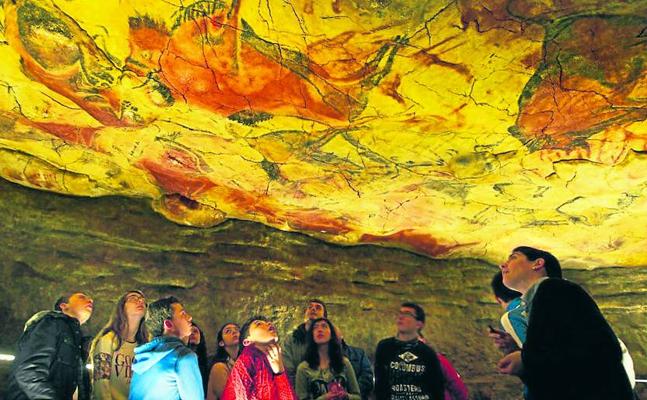 Un grupo de escolares examina el techo de bisontes de la neocueva de Altamira./