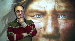 El paleogenetista Carles Lalueza-Fox posa delante de una recreación de un rostro de neandertal en la Biblioteca de Bidebarrieta, en Bilbao. / Ignacio Pérez/