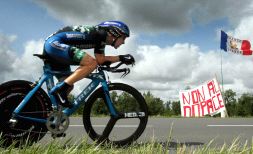 CONTRASTE. Leipheimer, en pleno esfuerzo durante la 'crono', pasa ante una pancarta que pide el final del dopaje. / EFE/