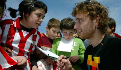 ADMIRADO. Fernando Amorebieta firma autógrafos a los niños el miércoles en Lezama. / JORDY ALEMANY/