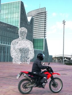 Un motorista circula por el recinto vacío de la Expo de Zaragoza, con la escultura 'El alma del Ebro' de fondo. / M. BARTOLOMÉ/