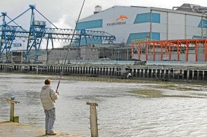 Un hombre pesca frente a la Acería Compacta de Bizkaia (ACB), propiedad de ArcelorMittal./ E. C./