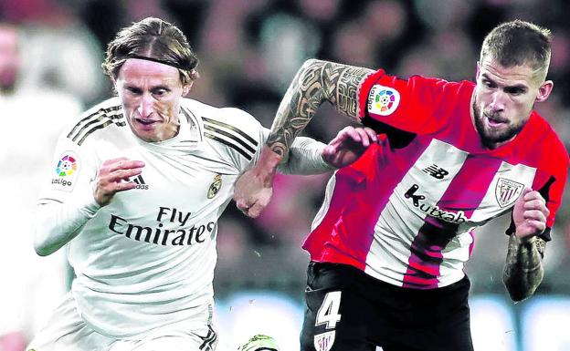 Iñigo Martínez, que no estará en el Bernabéu por sanción, trata de frenar al madridista Modric. 
