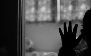 Una niña extiende la mano sobre una ventana./Óscar Chamorro