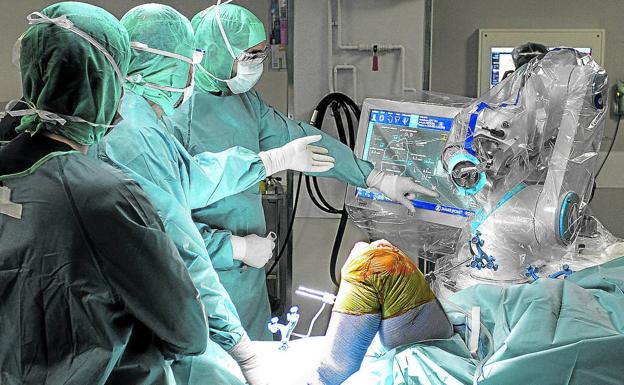 Luisa pone su rodilla en las manos de un robot de Cruces