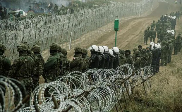 Polscy policjanci i żołnierze strzegą ogrodzenia oddzielającego ich terytorium od Białorusi.
