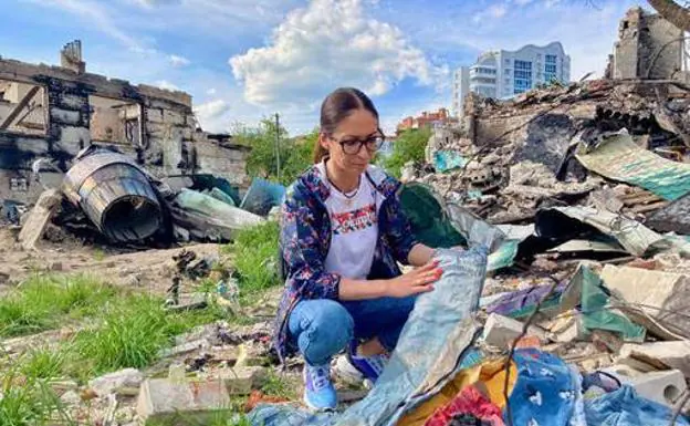 Yulia goes through a pile of children's pants in the rubble.