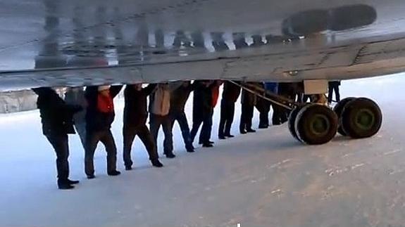 Pasajeros empujan su avión en un aeropuerto siberiano para poder despegar